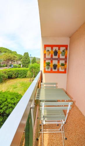 un balcon avec des chaises vertes et un tableau sur le mur dans l'établissement Studio Cabine neuf 4 personnes - Bormes les Mimosas - 300m de la plage de La Favière, à Bormes-les-Mimosas
