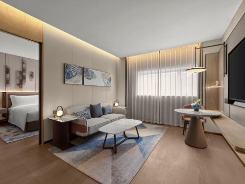 a living room with a couch and a bed at Hilton Shanghai Greater Hongqiao in Shanghai
