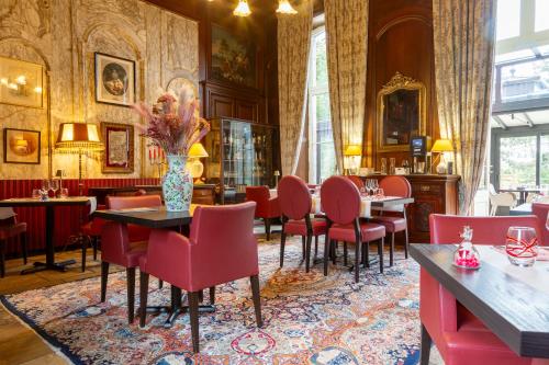 a restaurant with red chairs and tables and a vase of flowers at Château Hôtel Du Colombier in Saint Malo