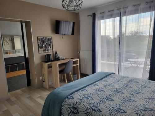 Un dormitorio con una cama y un escritorio y una ventana. en Chambres d'hôtes dans maison contemporaine, en Vernouillet
