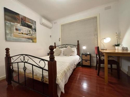 a bedroom with a bed and a desk and a window at Garden Guesthouse - Melbourne Airport Accommodation in Melbourne