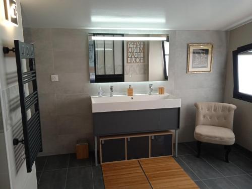 Un baño con lavabo y silla en Chambres d'hôtes dans maison contemporaine, en Vernouillet