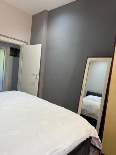 a bedroom with a white bed and a mirror at Lukas Apartament Vollga Durres in Durrës
