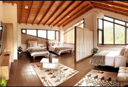 a bedroom with two beds and a living room with windows at Villa Germana in Paipa