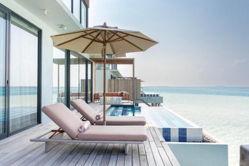 a group of chairs and an umbrella on the beach at SO/ Maldives in South Male Atoll