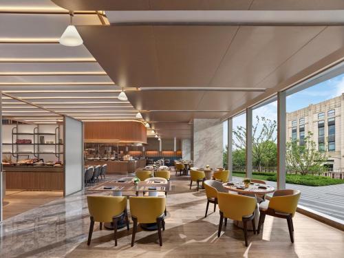 a restaurant with yellow chairs and tables and windows at Hilton Shanghai Greater Hongqiao in Shanghai