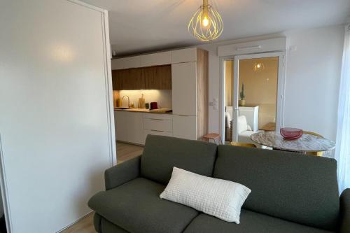 un salon avec un canapé vert et une cuisine dans l'établissement Modern studio - terrace - pool, à Villeneuve-Loubet