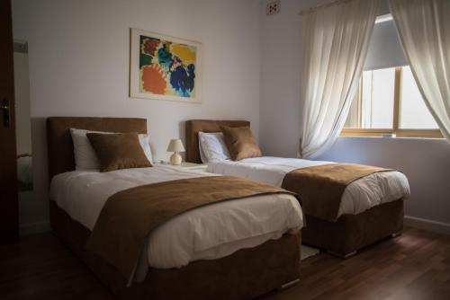 2 Betten in einem Schlafzimmer mit Fenster in der Unterkunft San Salvatore in St Julian's
