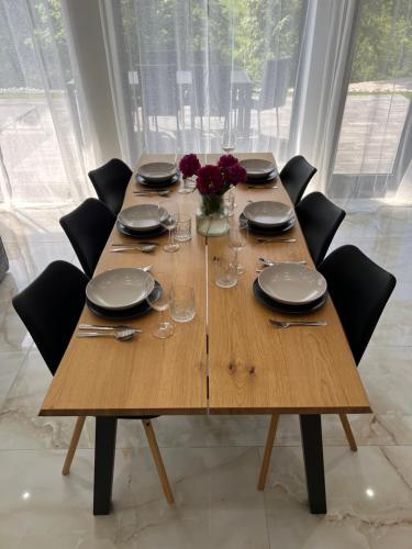 a wooden table with black chairs and plates and glasses at Podhorský Apartmány Terchová in Terchová