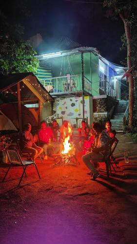 a group of people sitting around a fire at night at Green porticos villa munnar #MUNNAR in Anachal