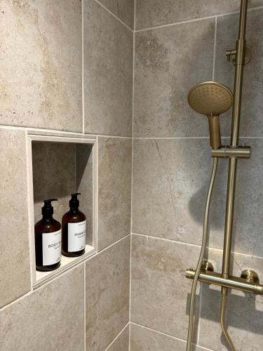 deux bouteilles de savon assises sur une étagère dans une douche dans l'établissement Le Nid Sainte-Catherine, à Honfleur
