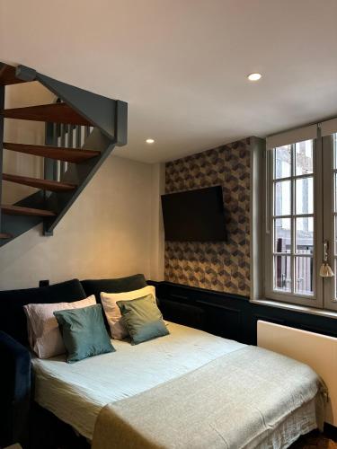 a bedroom with a bed and a stair case at Le Nid Sainte-Catherine in Honfleur