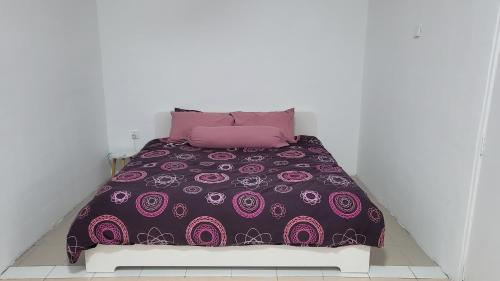a bed with a purple comforter and pink pillows at Homestay H&H in Cyberjaya