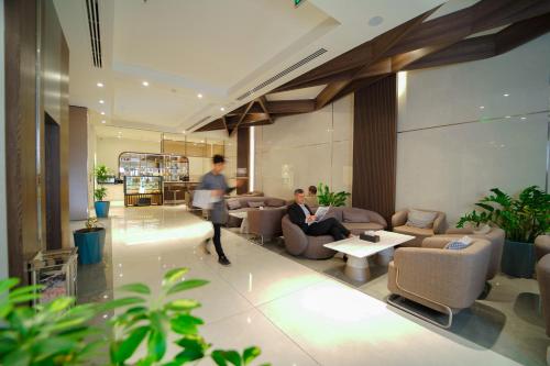 a woman walking through a lobby with a man sitting on a couch at Darin Plaza Hotel in Erbil