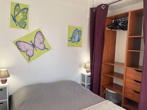 une chambre avec des photos de papillons sur le mur dans l'établissement CAPAO Joli 2 pièces cabine piscine Richelieu Cap d'Agde, au Cap d'Agde