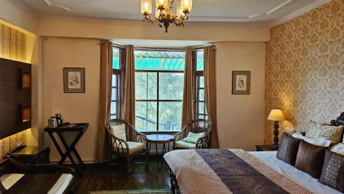 a bedroom with a bed and a table and a window at StayVista at Raas Villa with BBQ & Bonfire in Chail
