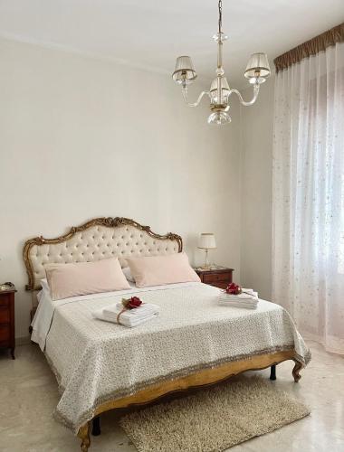 una camera bianca con un grande letto e un lampadario a braccio di Maison Le Calle B&b a San Giorgio Ionico