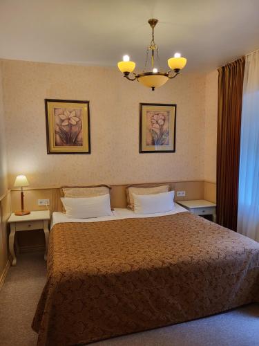 a bedroom with a bed and two tables and a chandelier at Vila Florena Garden in Palanga