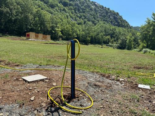 a yellow hose tied to a pole in a field at Camping-Baven-Toven Naturae in (( Bulshizë ))