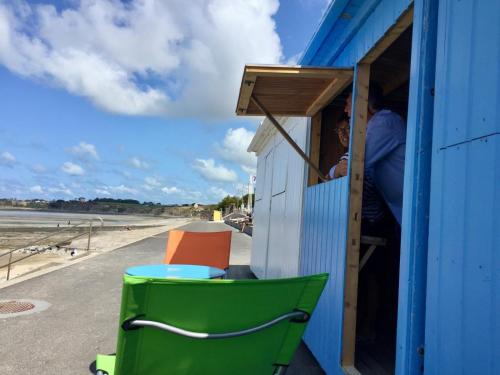 a person looking out the window of a blue shack at Très proche Granville Résidence Midship in Saint-Pair-sur-Mer