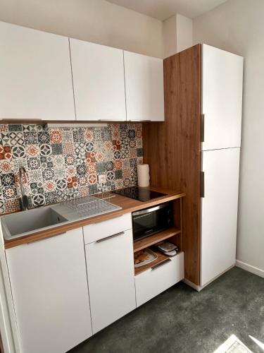 une petite cuisine avec des armoires blanches et un micro-ondes dans l'établissement 17 Rue du Puits de la Place, à Granville