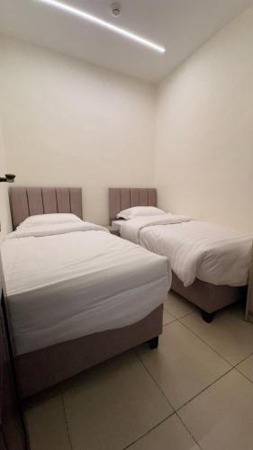two beds in a room with white walls at يزن للاجنحة الفندقية in Aqaba