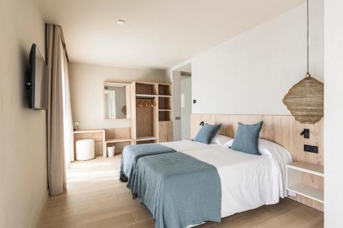a bedroom with a large bed with blue pillows at Hotel Casamar in Llafranc