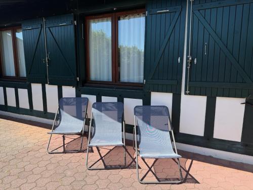 un groupe de trois chaises assises devant un bâtiment dans l'établissement Hossegor Plage, Maison landaise 6 personnes, à Soorts-Hossegor