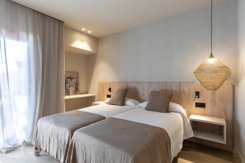 a bedroom with two beds and a large window at Hotel Casamar in Llafranc
