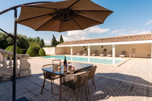 - une terrasse avec une table et un parasol à côté de la piscine dans l'établissement Coeur Cristal - Maison de maître & Ecolodge avec piscine et jardin, à Magalas