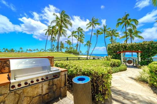 a outdoor kitchen with a grill and palm trees at KBM Resorts FREE CAR Beach Villas at Ko Olina BVK-B-308 Beachfront Villa in Kapolei