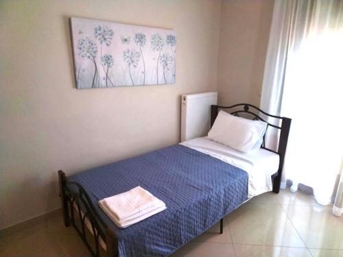 a bedroom with a bed with a blue blanket and a painting at Rias house in Néa Péramos