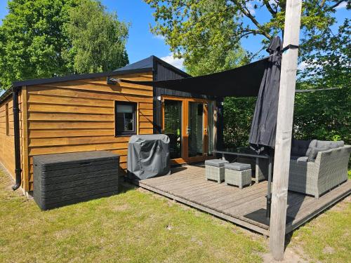 a cabin with a black awning on a deck at Woodcabin op de Lente van Drenthe in Gasselte