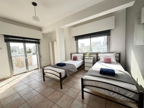a bedroom with two beds and a large window at Adonis Holiday Apt - Nicosia in Nicosia