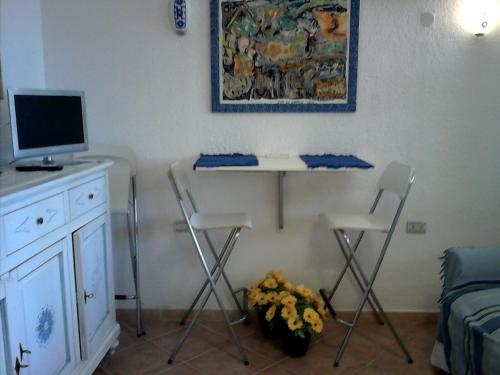 a room with a desk with two chairs and a computer at Bilocale presso Costa Smeralda in Cugnana Verde