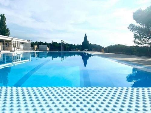 une grande piscine avec de l'eau bleue dans l'établissement Lumineuse villa au pied de la pinède, à Lézignan-Corbières