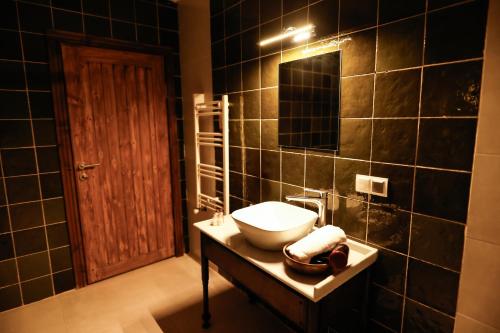 a black tiled bathroom with a sink and a mirror at Ayaz Stone House in Goreme
