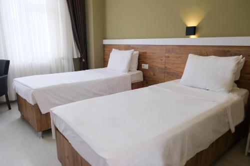 two beds in a hotel room with white sheets at Altayhan Otel in Amasya