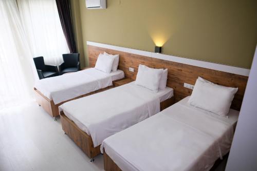 a hotel room with three beds and a chair at Altayhan Otel in Amasya