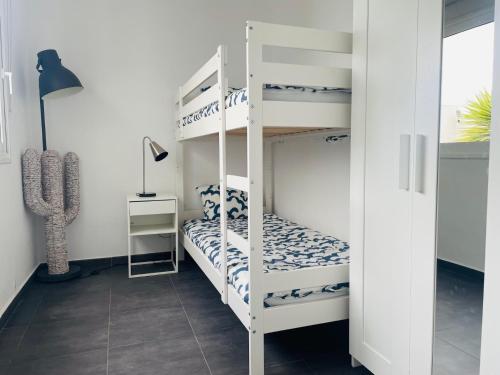 a bedroom with two bunk beds and a lamp at Villa Neo - Private Pool - 8 minutes Corralejo, mini Gym!! in Villaverde