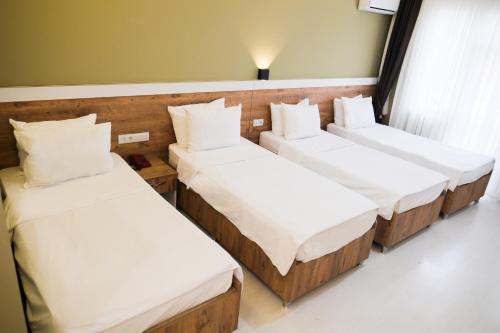 three beds in a room with white pillows at Altayhan Otel in Amasya