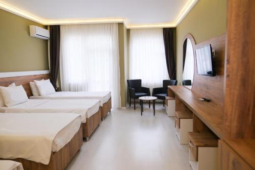a hotel room with two beds and a table and chairs at Altayhan Otel in Amasya