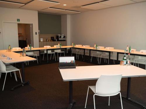 a large room with tables and white chairs at C-Hotels Westwing - ex Mercure in Roeselare