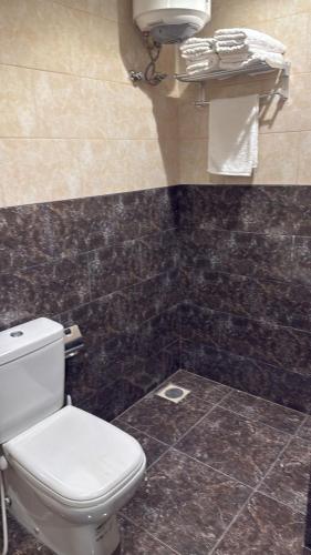 a bathroom with a toilet and a black tiled wall at أصداء البحر للشقق المخدومة in Yanbu