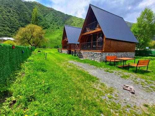 a log cabin with a table and benches in the grass at Panorama cottages in Sno in Sno