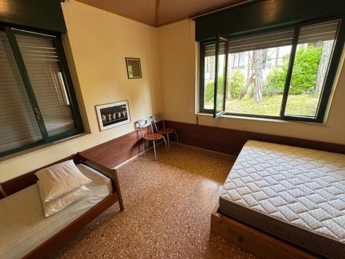 1 dormitorio con 1 cama, 2 ventanas y mesa en Villa Pineta - Parcheggio, Giardino, Wi-Fi, Tavolo Ping Pong - Oasi di Tranquillità a Due Passi dal Mare, en Lignano Sabbiadoro