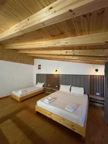 two beds in a room with wooden ceilings at Sea's Villa in Ksamil