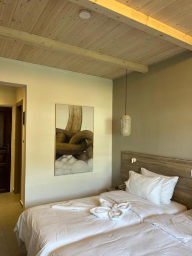 a bed with white sheets and a painting on the wall at Paradise Hotel in Samos
