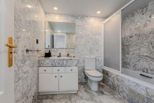 a white bathroom with a toilet and a sink at New Renovated Front Line Beach Playa Rocio Puerto Banus in Marbella