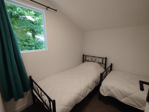 deux lits jumeaux dans une chambre avec fenêtre dans l'établissement Camping de BAIRON, à Le Chesne